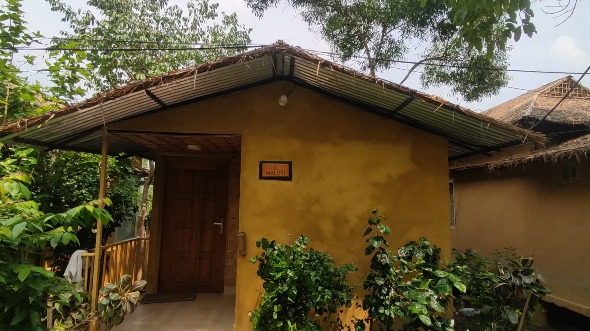 The 'Maloti' luxury cottage at Arannyo Nibas Eco Resort, a mud-plastered hut with a thatched roof and named door plaque