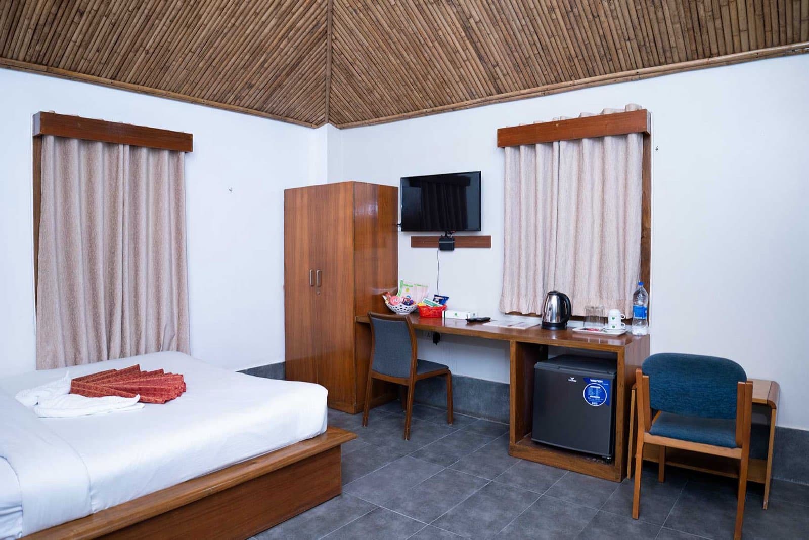 A couple cottage room at Balishira Resort with a bamboo ceiling and wooden furnishings