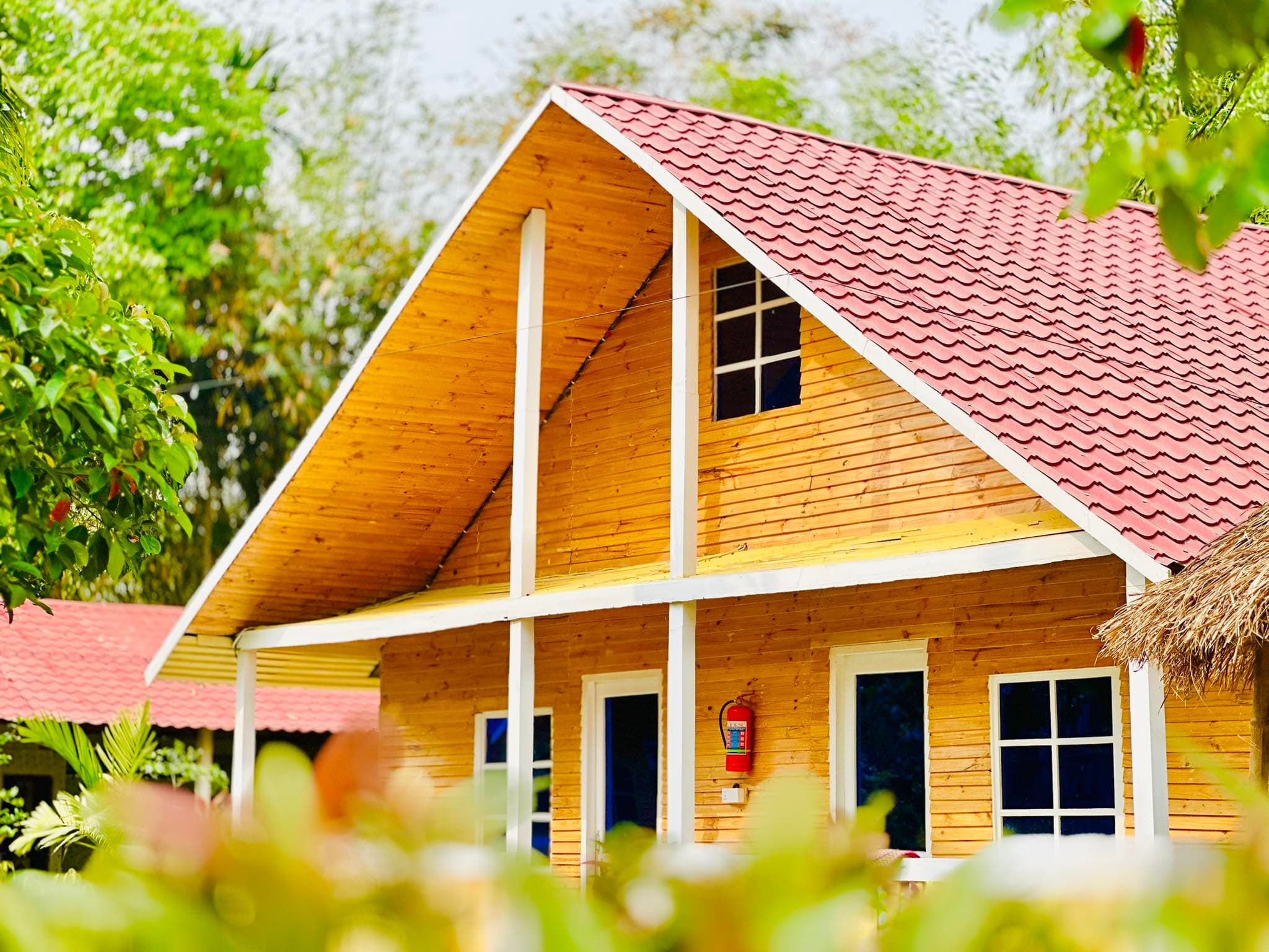 A-frame wooden cottage with red tiled roof at Banabithi Eco Resort, family room 105