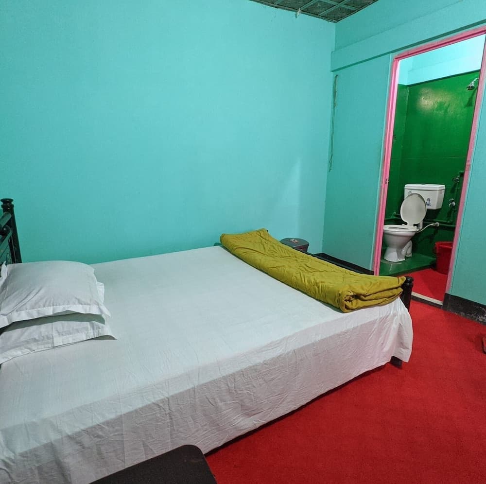 Teal-walled guest room with a double bed and an attached green-tiled ensuite bathroom