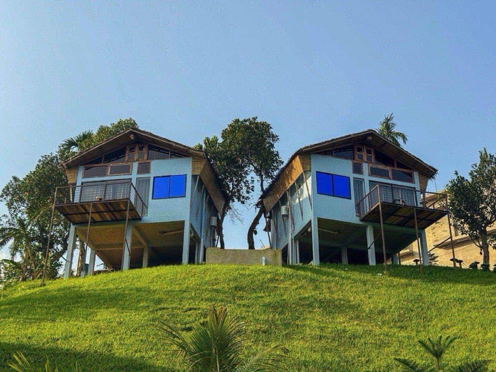 Two elevated cottages at Bonsai Eco Village set on a green hillside