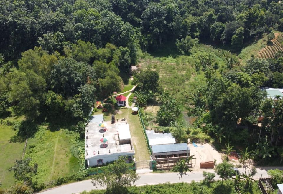 Aerial view of Chader Bari Eco Resort's buildings and garden, ringed by forested hillside