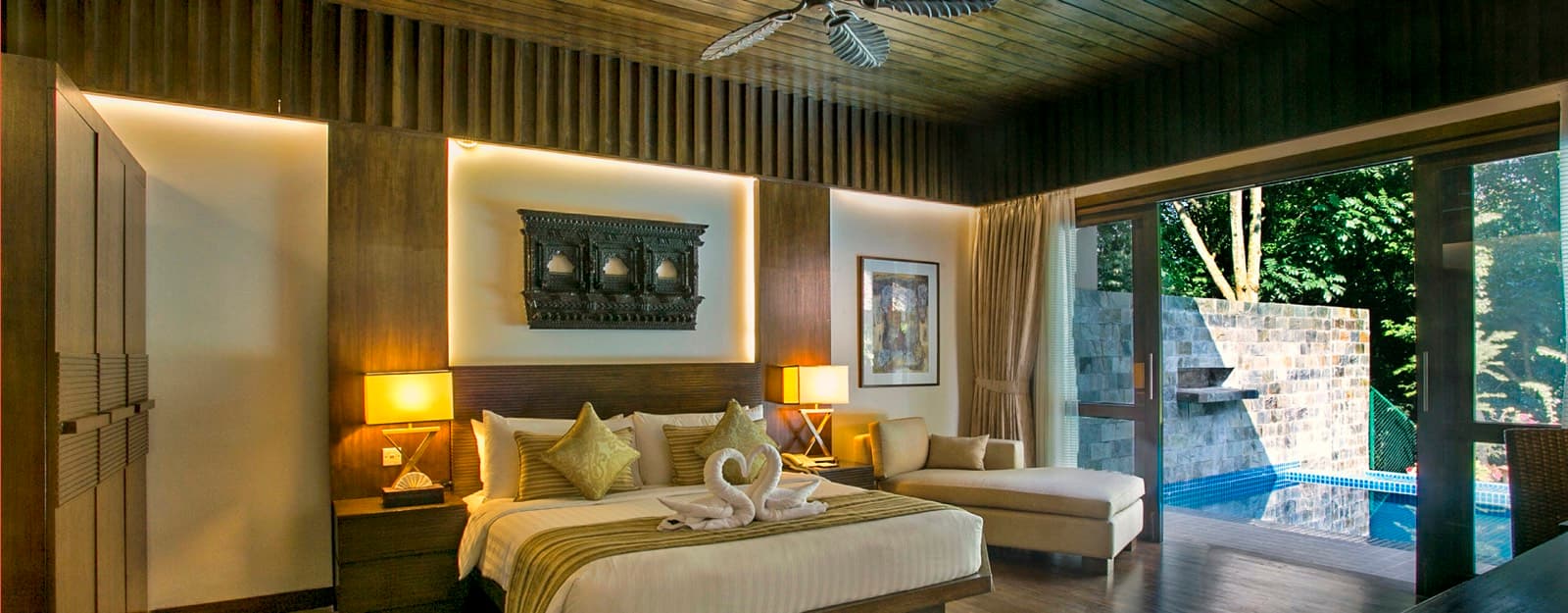 A villa bedroom at DuSai Resort & Spa opening onto a private pool and forest view