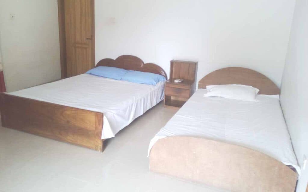 A twin-bed room at Garden View Guest House with plain white bedding and a bedside table