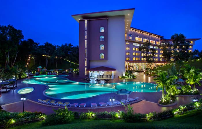 Grand Sultan's curved swimming pool and jacuzzi lit up at night beside the main tower, sun loungers along the deck