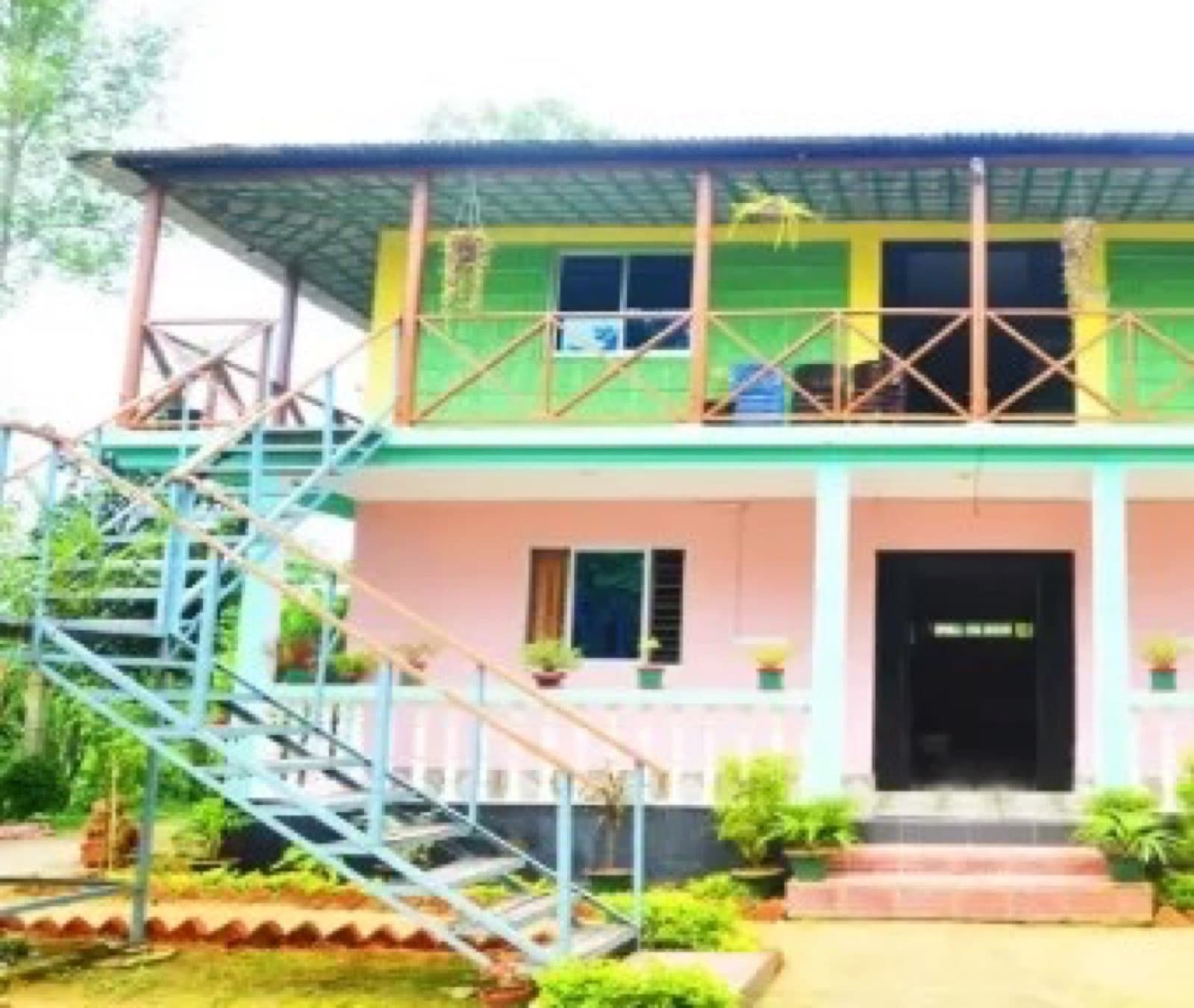 The colourful two-storey building of Green Palace Tea Resort with an outdoor staircase