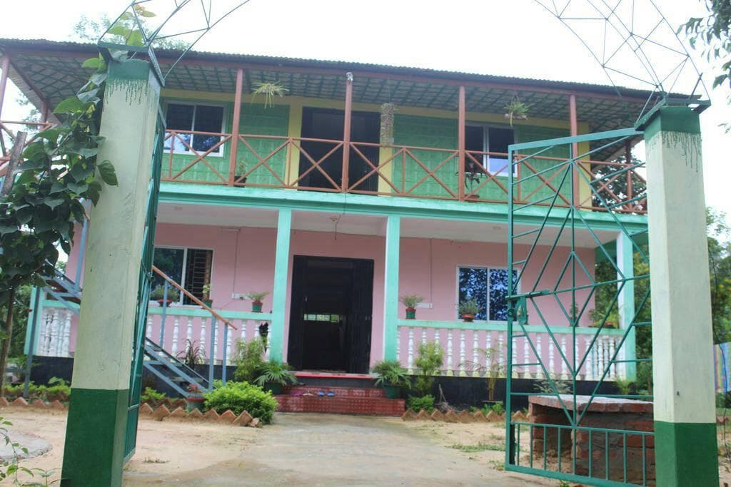 Front entrance gate view of Green Palace Tea Resort's pink and green two-storey building with a covered veranda