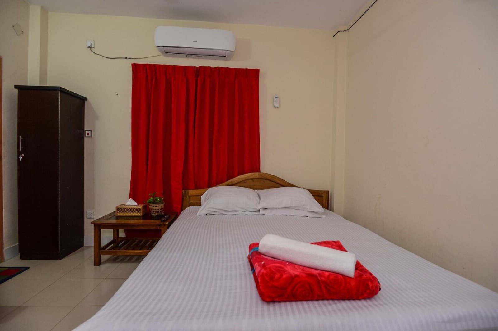 A bedroom at Himachol Resort with a double bed, red curtains, and a wardrobe
