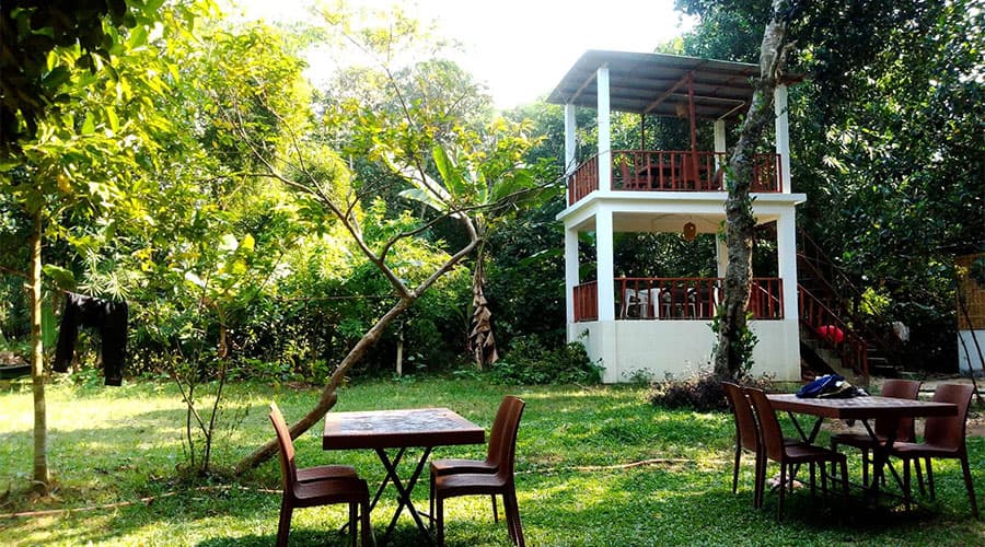 A two-storey open-air pavilion at Himkuri Bon Bungalow with garden dining tables set on the lawn