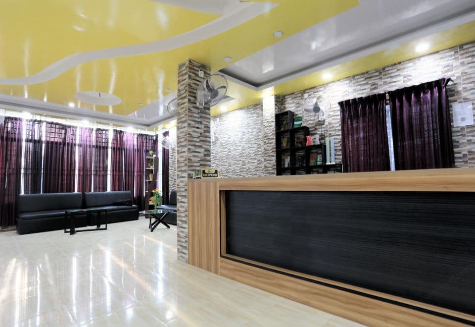 Hotel Merina's reception lounge with a stone-tiled wall, black sofas, and a wood-panelled front desk