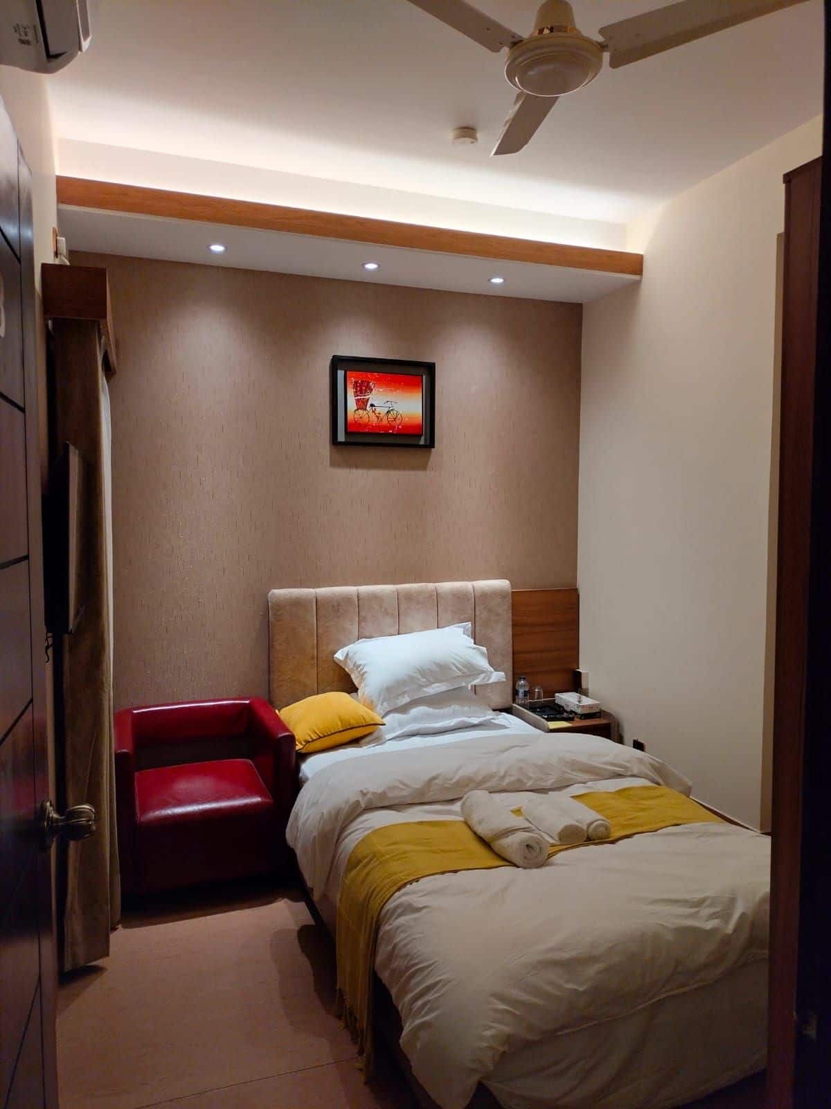 Hotel Taj Metro single room with a red armchair and a framed rickshaw-art print above the bed