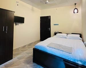 The Jol Jonaki room at Joldhara Resort with a dark wooden bed, wardrobe, and wall-mounted TV