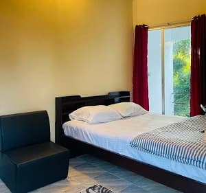The Osto Chad room at Joldhara Resort with red curtains and a glass balcony door