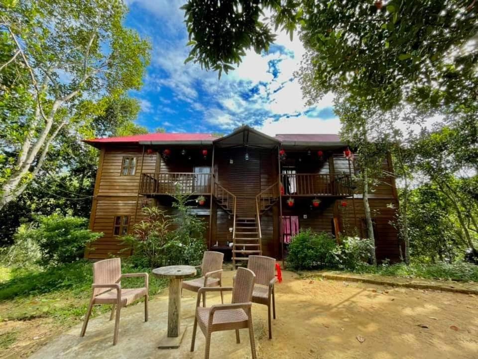 Jungle Cottage's two-storey wooden building with a red roof and balconies, seen from the forecourt seating area