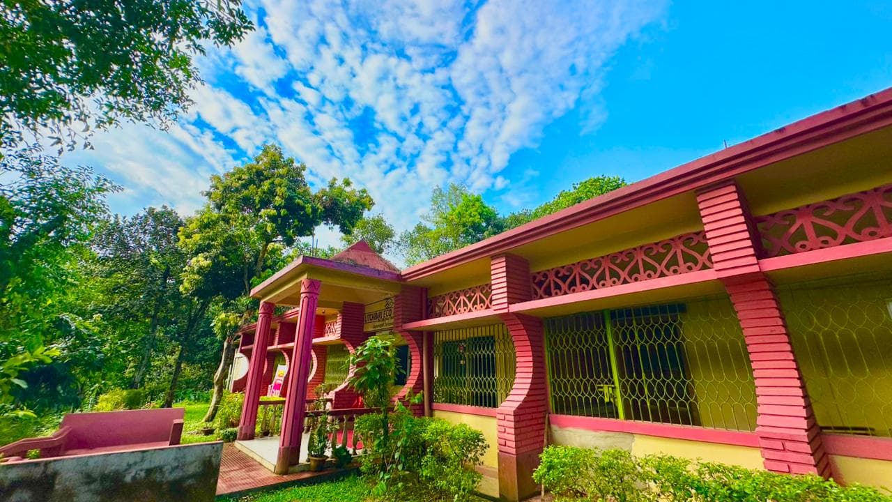 Litchibari Eco Resort's pink-columned reception building, with 'Litchibari Eco' signage visible over the entrance