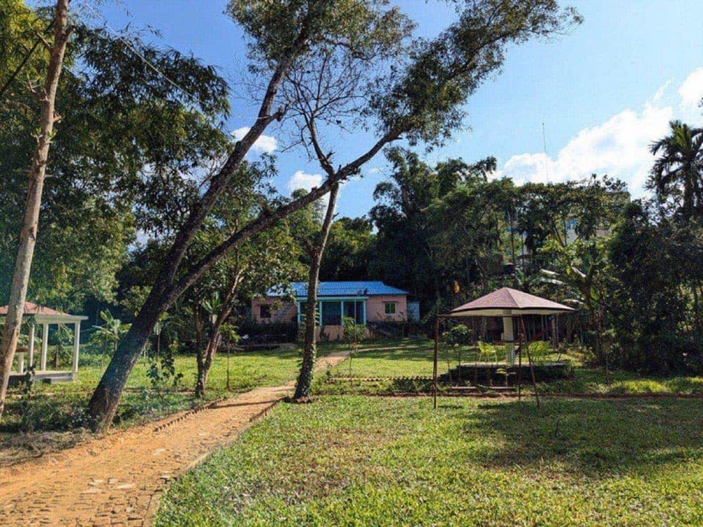 A pink cottage set among trees at Megher Bari Eco Resort with a gazebo nearby