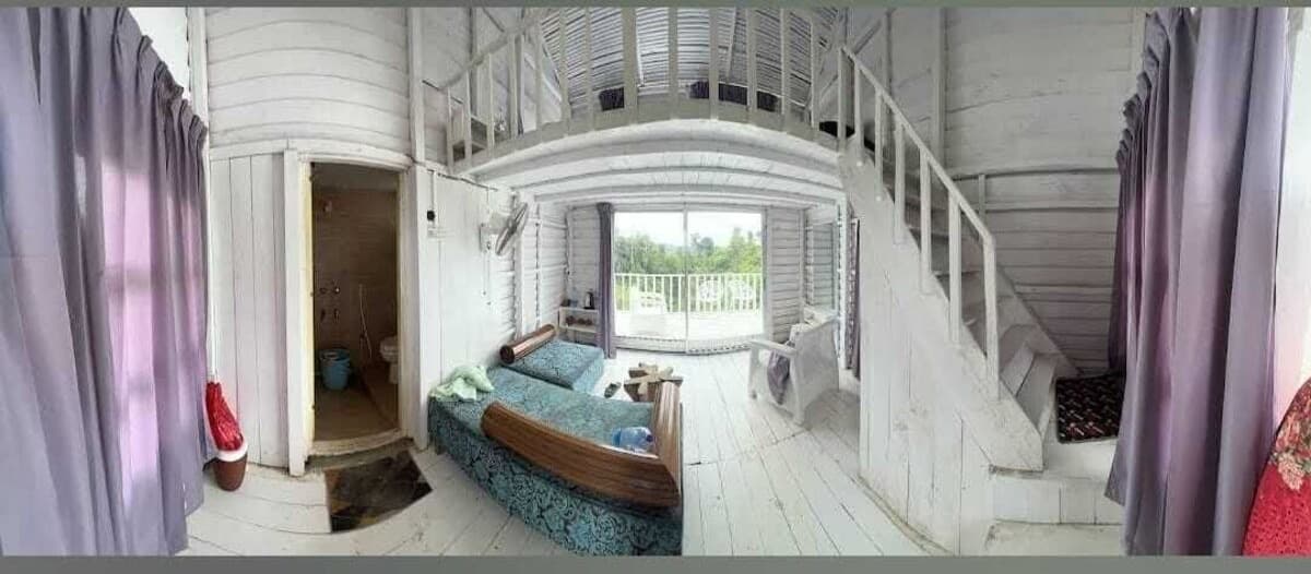 A wooden duplex cottage interior at Nihom Eco Resort with a loft and garden-view balcony
