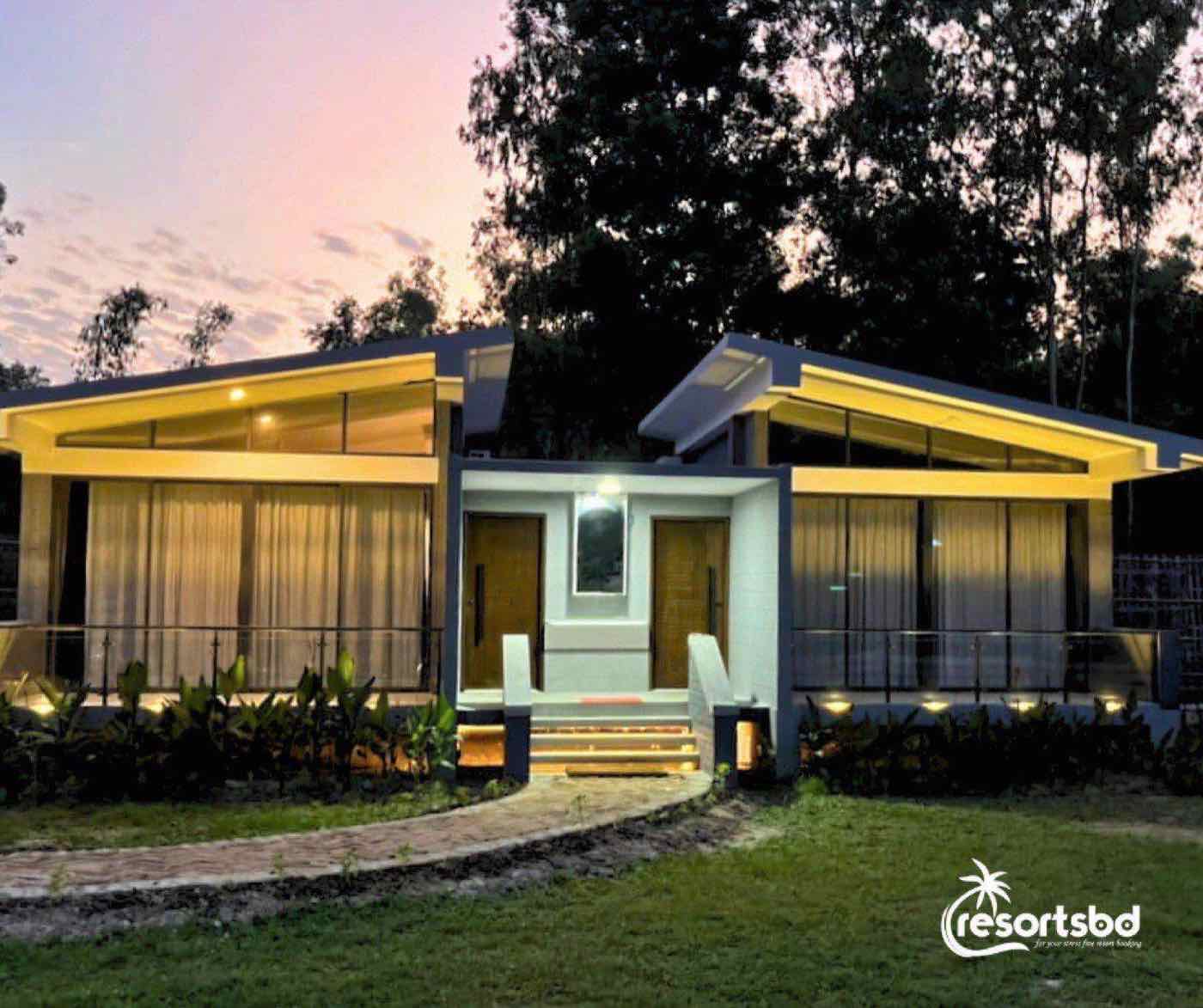 Oronner Din Ratri Resort's cottage lit up at dusk with a stone garden pathway
