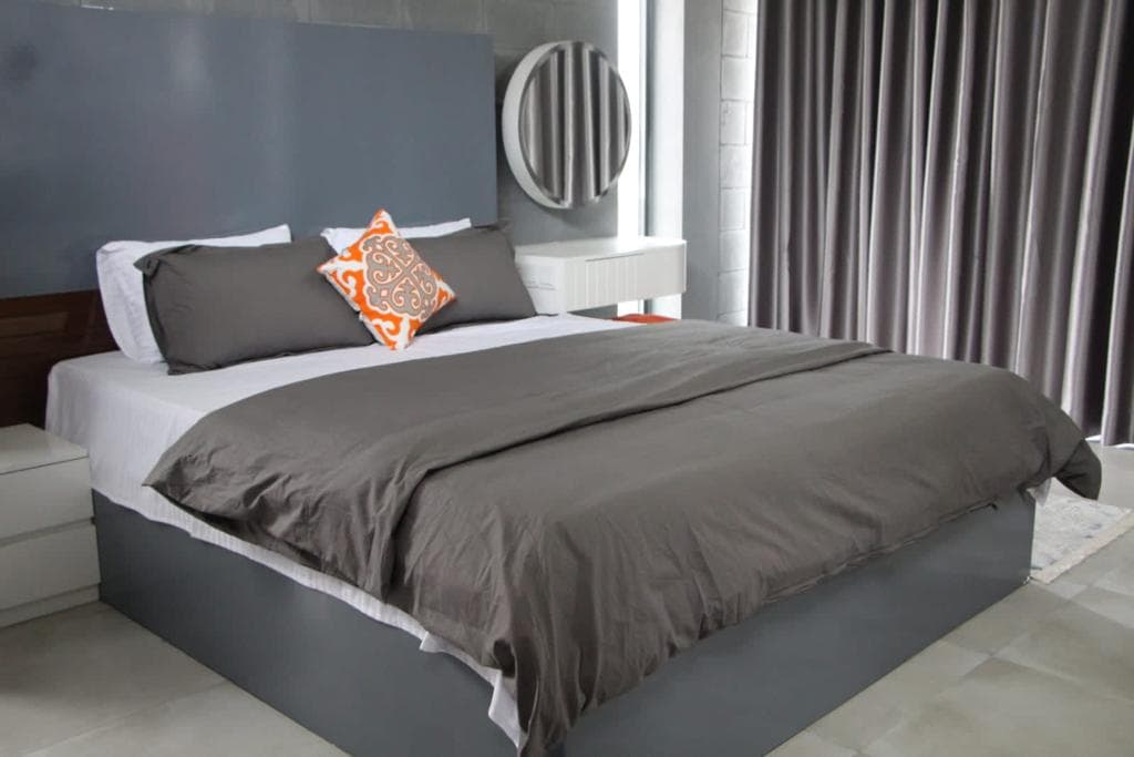 A grey-and-orange styled room at Oronner Din Ratri Resort with a round mirror and floor-to-ceiling curtains
