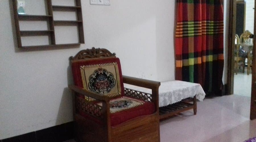 A carved wooden armchair and side table in a sitting area with striped curtains