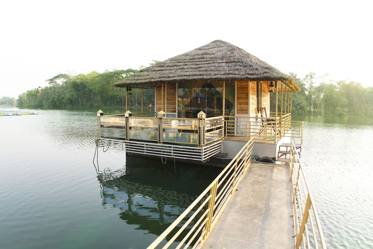 Rangauti Resort's thatched-roof floating room on the lake, reached by a long footbridge, at sunrise