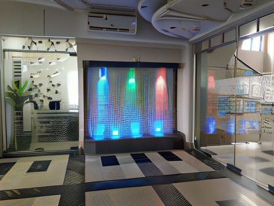 Lobby nook with a mirrored glass wall panel and a colourful backlit LED water-curtain feature