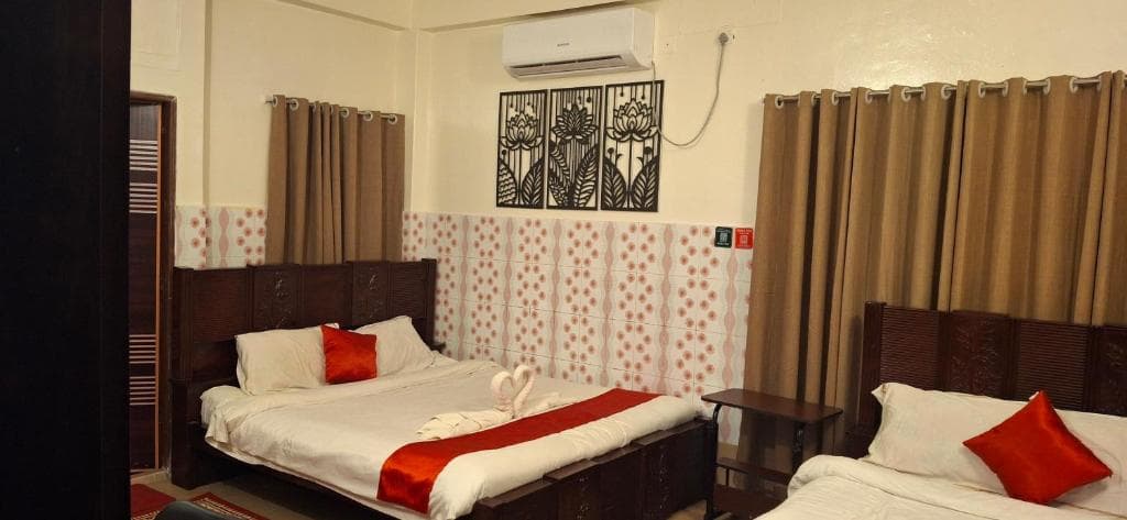 A family room at Rose Inn with two double beds, an air conditioner and curtained windows
