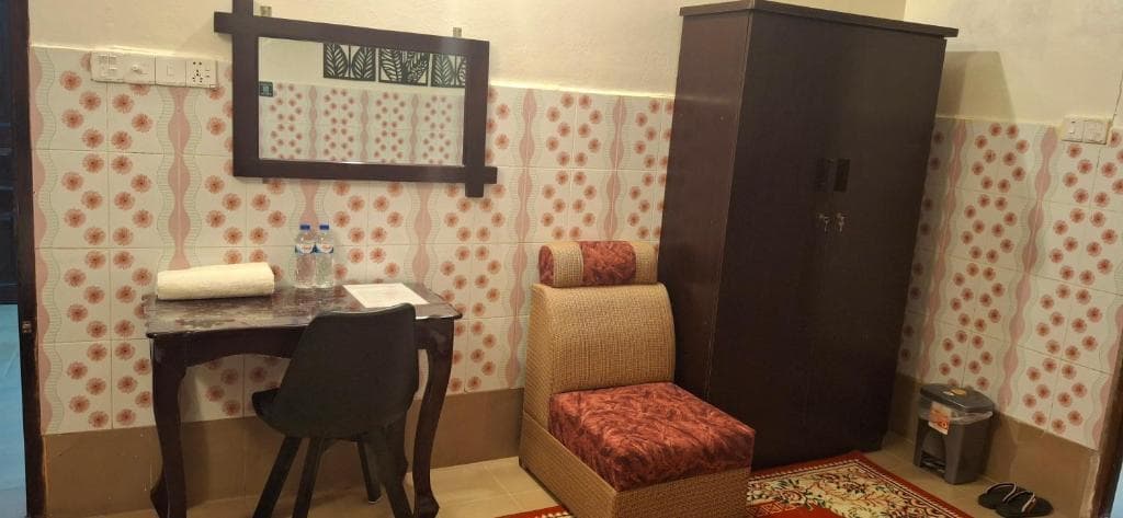 A writing desk, chair, bench seat and wardrobe in a Rose Inn guest room