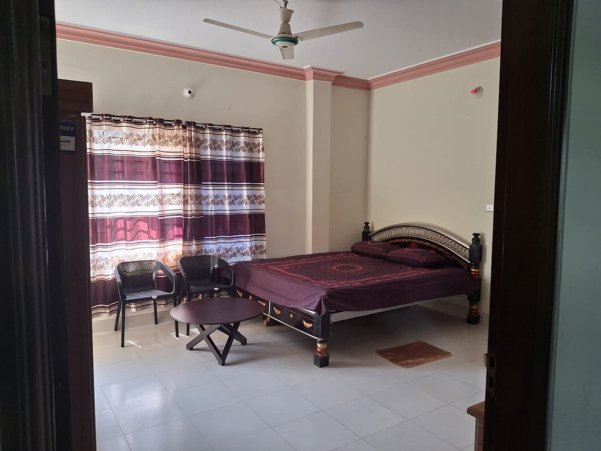 Master bedroom with double bed, maroon bedding and patterned curtains