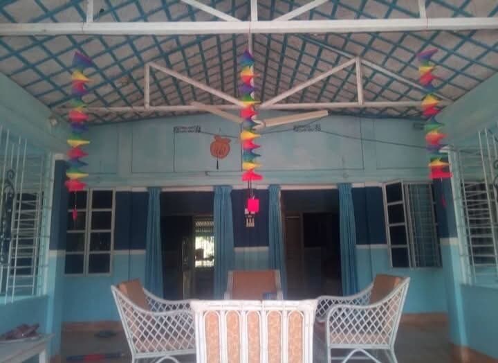 Covered veranda seating area with white wicker chairs under a lattice ceiling strung with colourful hanging decorations