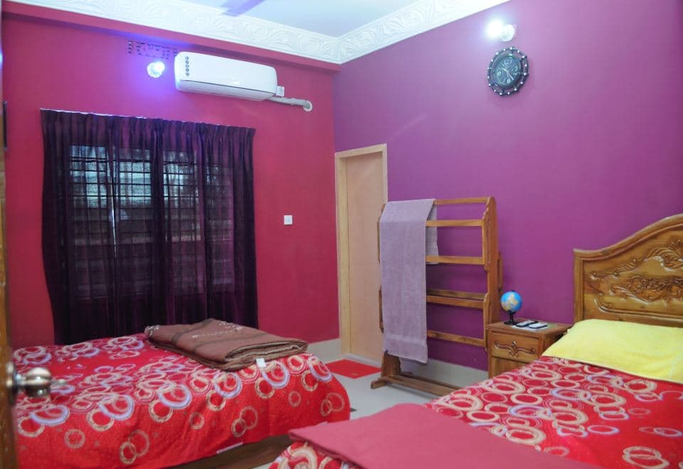 A magenta-walled twin room at Tamim Resort with red patterned bedspreads and a wall-mounted air conditioner