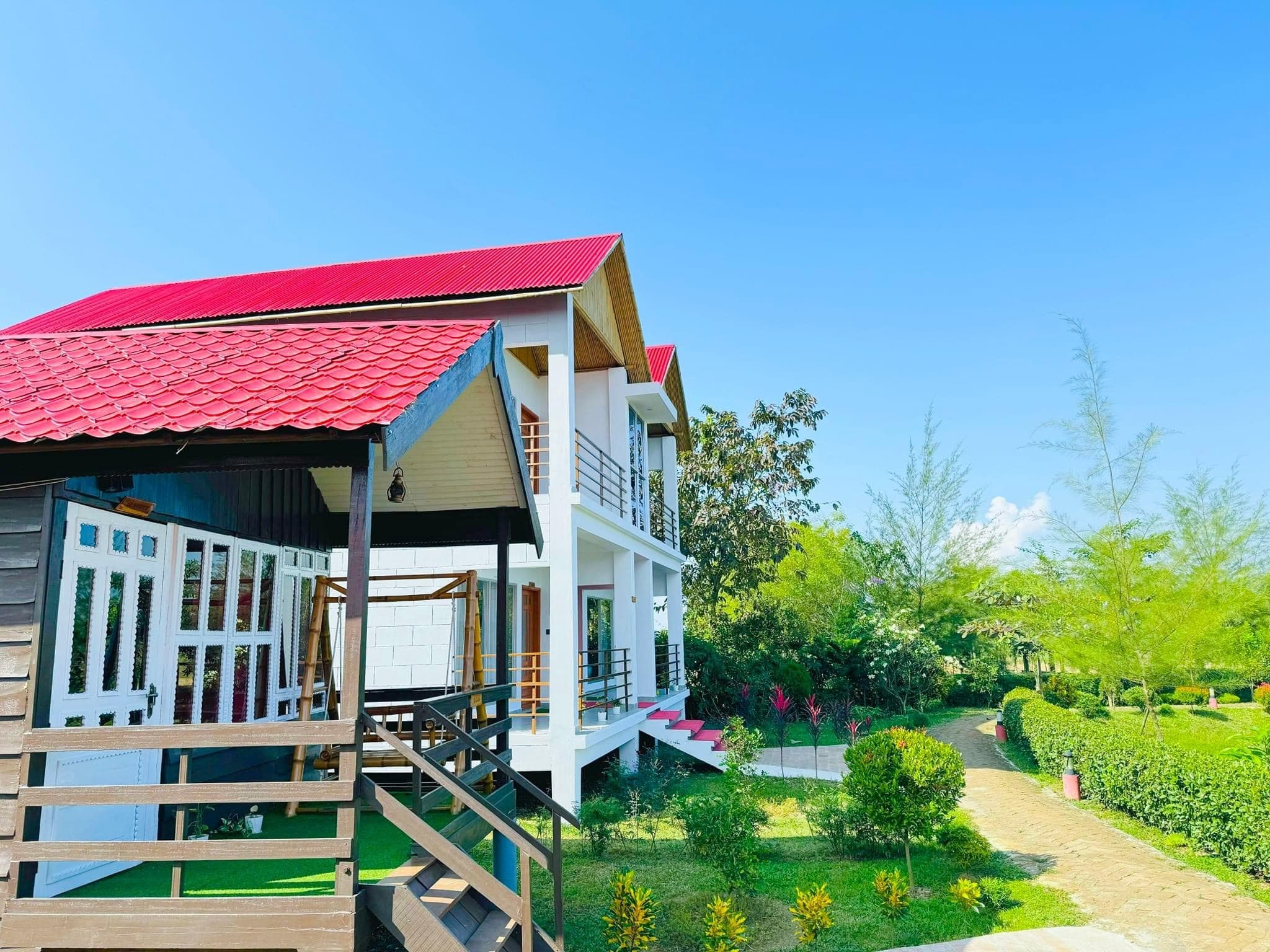 Daytime view of the red-roofed two-storey building and cottage porch with landscaped garden path