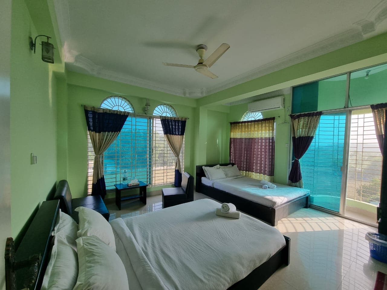 A twin-bed room at Grand Selim Resort with green walls, arched windows, and a balcony view over the countryside