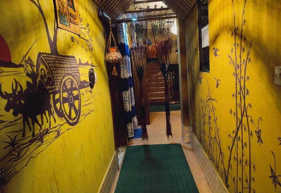 A hand-painted hallway at Green Leaf Guest House with a bullock-cart folk-art mural on bright yellow walls