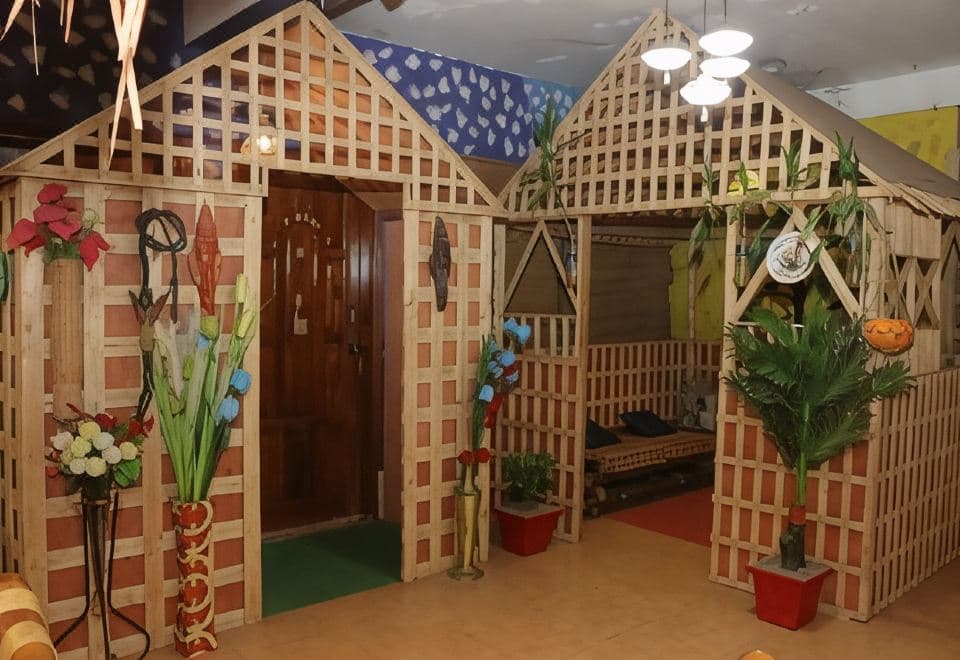 Whimsical lattice-fronted hut-style room entrances inside Green Leaf Guest House, decorated with plants and flowers