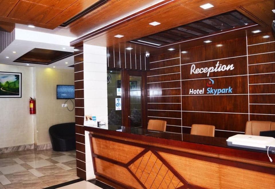 Hotel Skypark's wood-panelled reception desk with the hotel's logo and name lit up on the wall behind it