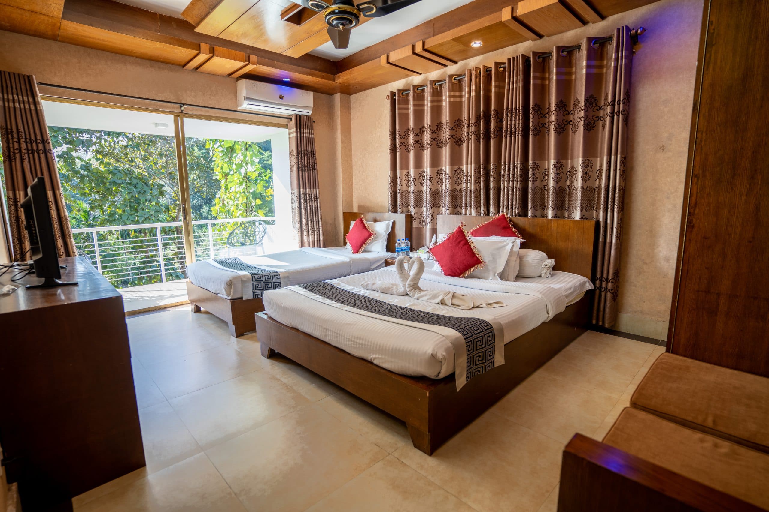 A twin-bed Luxury Suite at Lemon Garden with a private balcony overlooking trees and red accent cushions