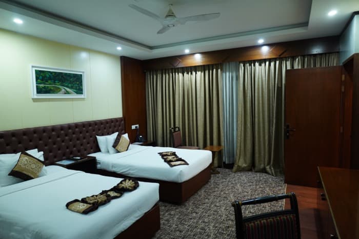 A Family Deluxe twin-bed room at Paragon with patterned throw cushions and heavy gold curtains