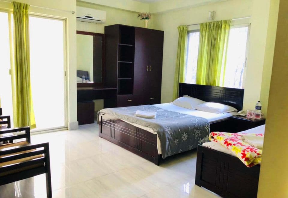 A room at Tea Heaven Resort with two beds, green curtains, a wardrobe, and a sliding balcony door