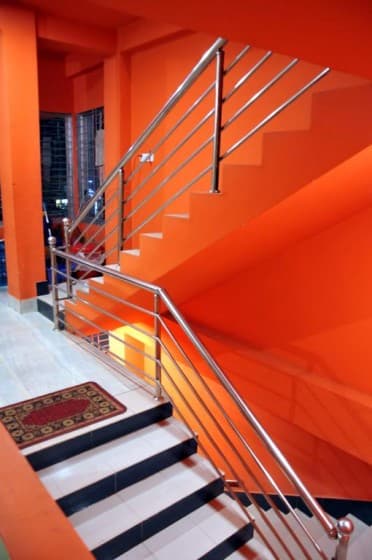 Orange stairwell with steel handrails and black-and-white striped stair treads